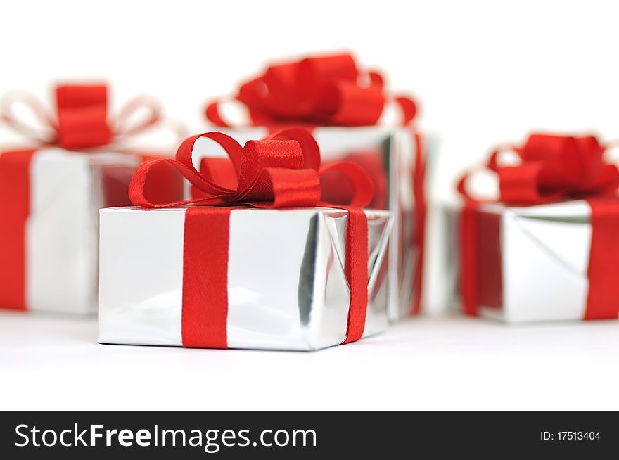 Gifts in silver wrapping with red bow isolated on white background. Gifts in silver wrapping with red bow isolated on white background