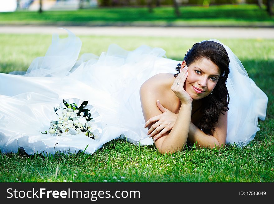 Happy bride on the grass in summer park