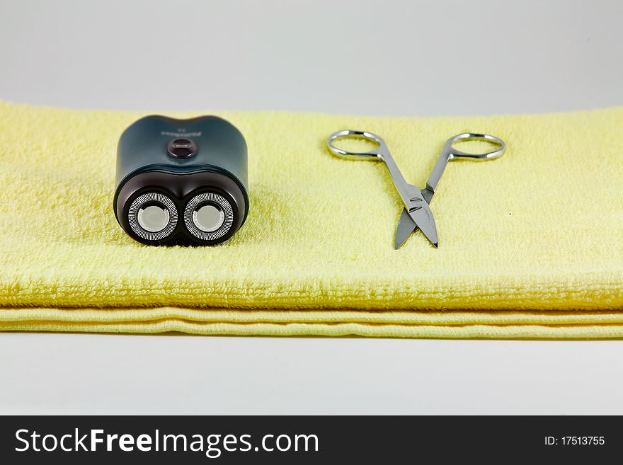 Shaver and scissor on yellow towel