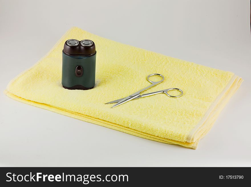 Shaver and scissor on yellow towel