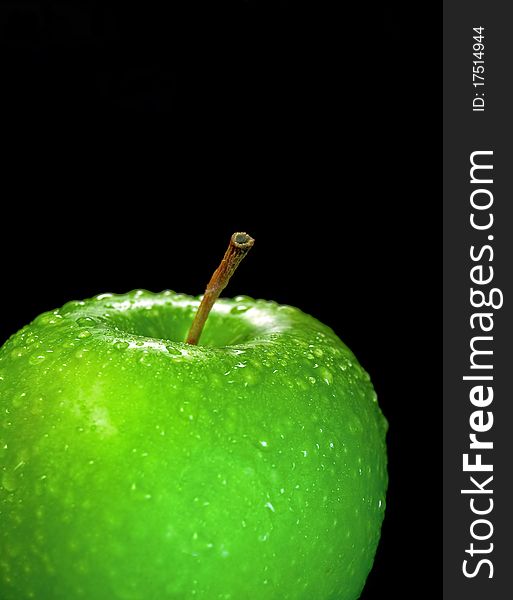 The Juicy green apple in drop of water on black background. The Juicy green apple in drop of water on black background.