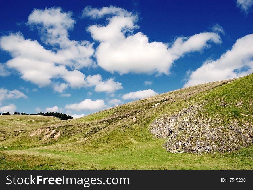 Beautiful alpine meadow with green grass and blue sky