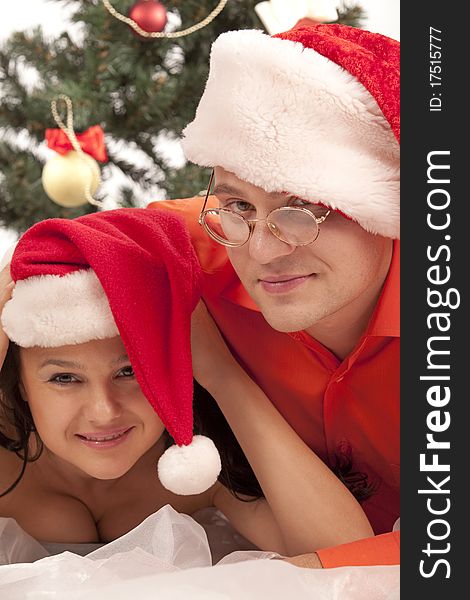 Young lovely couple near a Christmas tree. Isolated over white background