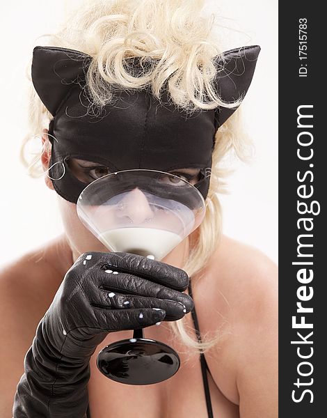 Portrait of the blond model wearing black cat, licking - drinking milk from the martini glass. Portrait of the blond model wearing black cat, licking - drinking milk from the martini glass