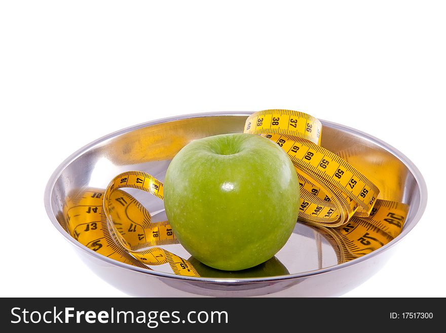 An apple with measure tape in a chrome bowl isolated over white