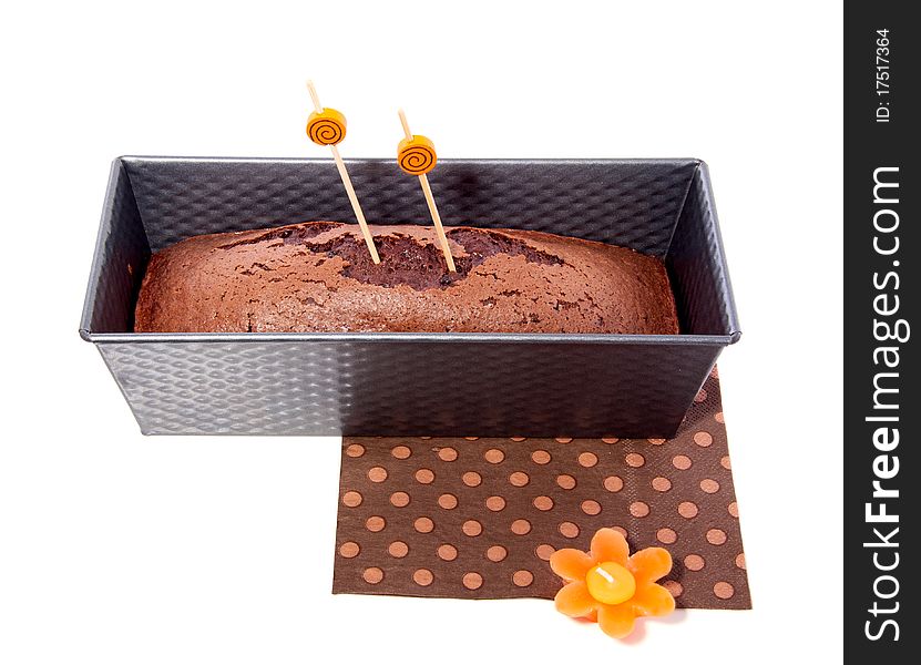 Home baked chocolate cake in a cake pan isolated over white