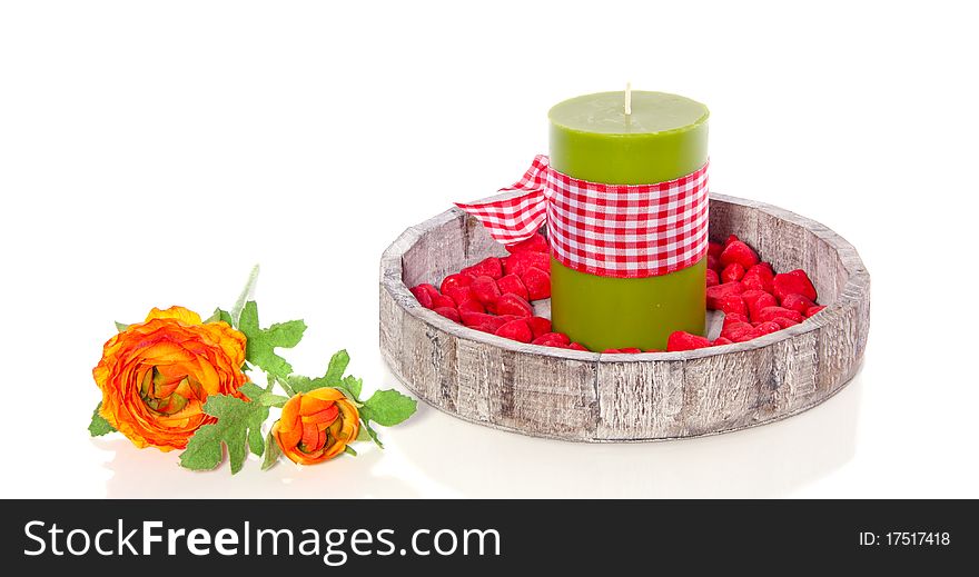 A wooden tray with a green candle decorated with stones and flowers isolated over white. A wooden tray with a green candle decorated with stones and flowers isolated over white