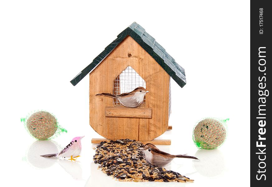 A birdhouse with birds and seeds isolated over white