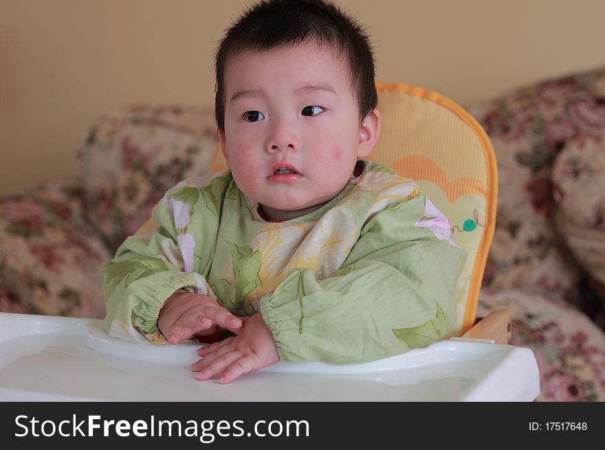 Lovely baby sitting on the baby chair at home. Lovely baby sitting on the baby chair at home