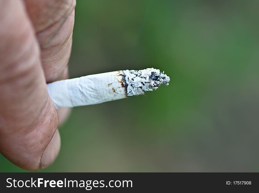 Cigarette in hand on a green background