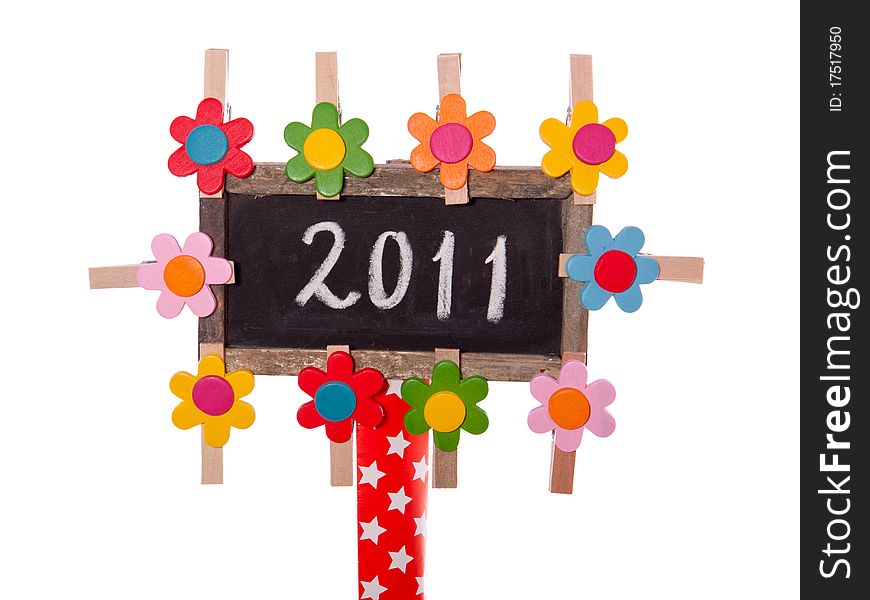 2011 written on a blackboard decorated with colorful wooden flowers isolated over white