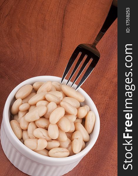 White canned beans in a white ceramic bowl with a fork. White canned beans in a white ceramic bowl with a fork.