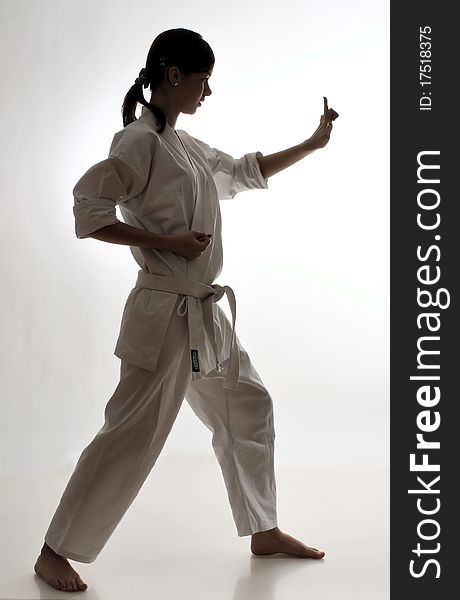 Profile of a girl practicing karate against grey gradient background; silhouette lighting setup
