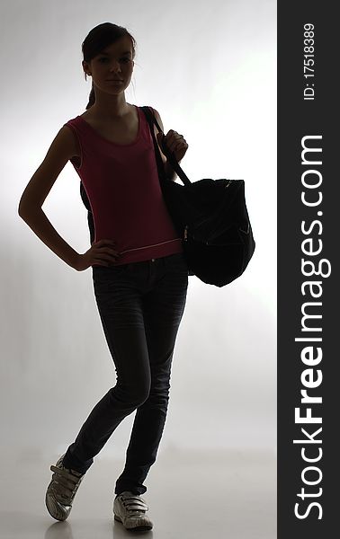Silhouette of a slim girl with a large sports bag against gray background. Silhouette of a slim girl with a large sports bag against gray background.