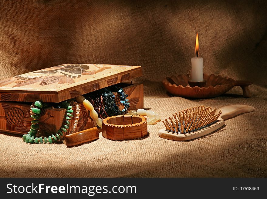 Still-life with wooden casket, ornaments, hairbrush and candle on textural background