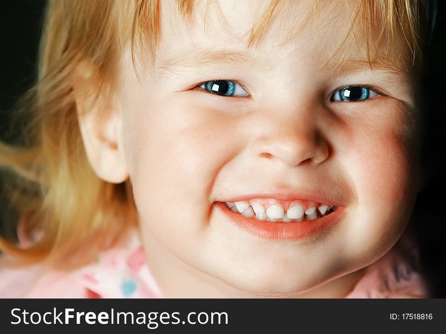 Portrait of the pretty smiling little girl with blue eyes close-up