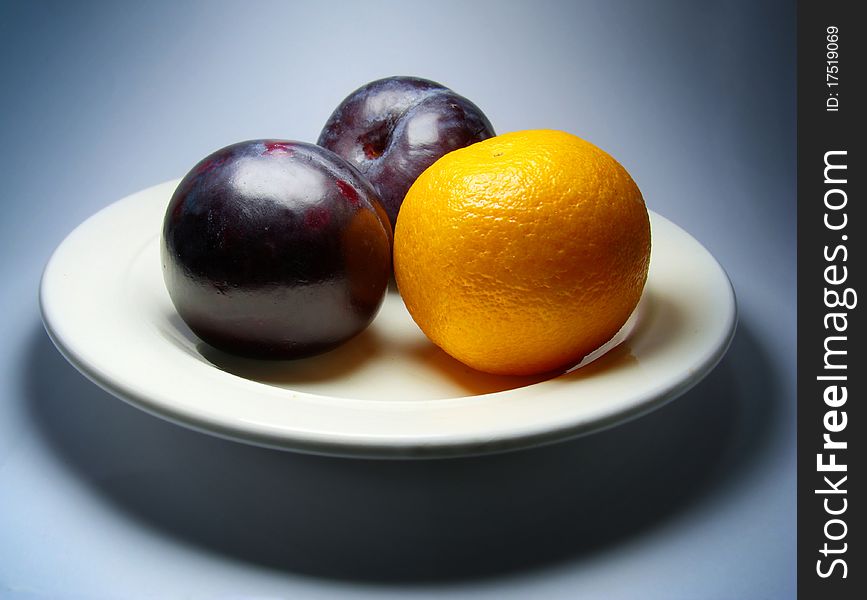 Plums And Tangerine On Plate.