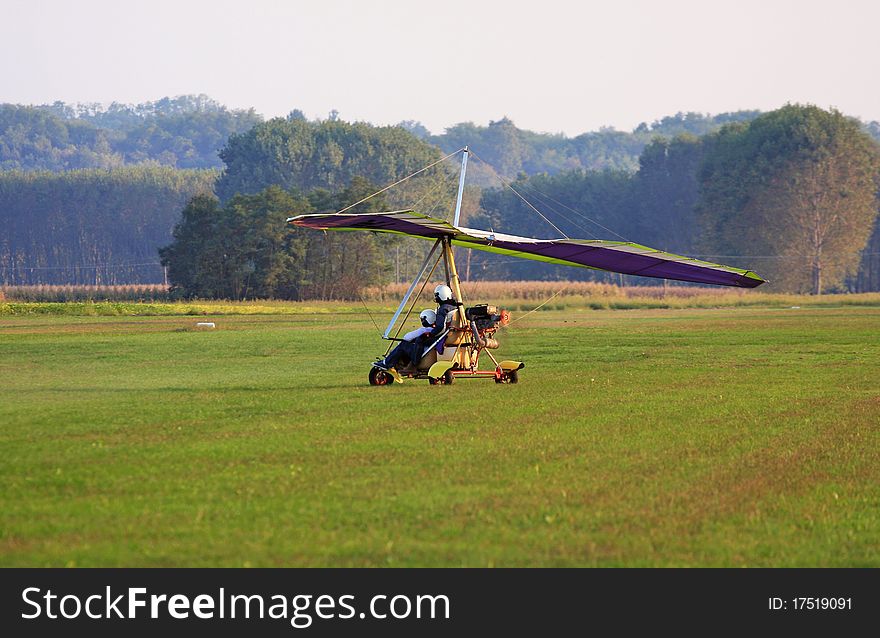 Hang glider is landing in a grain field