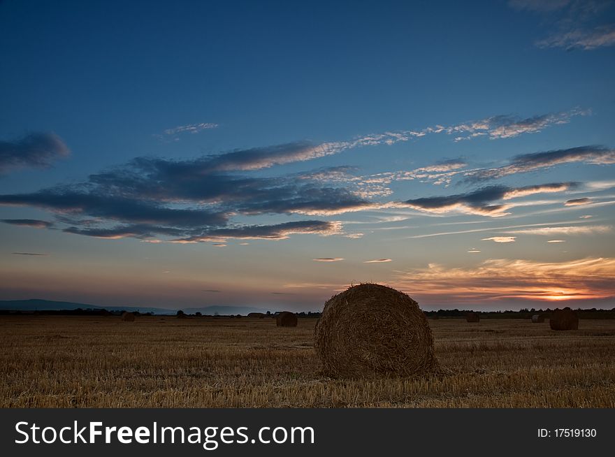 Straw bale on field on sunset time