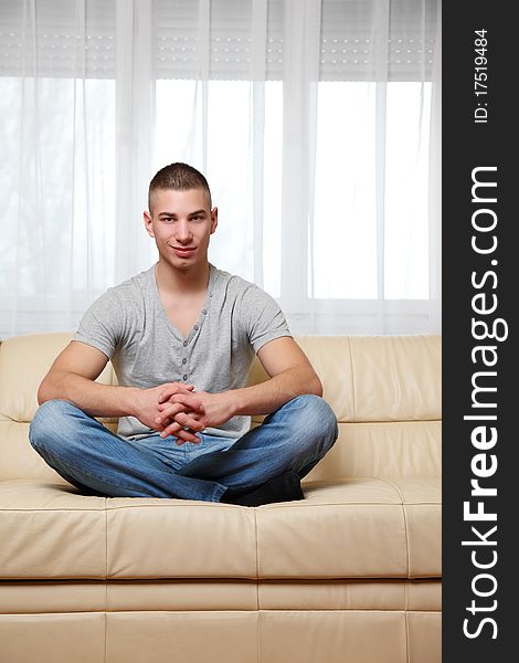 Young man making yoga pose on the sofa. Young man making yoga pose on the sofa