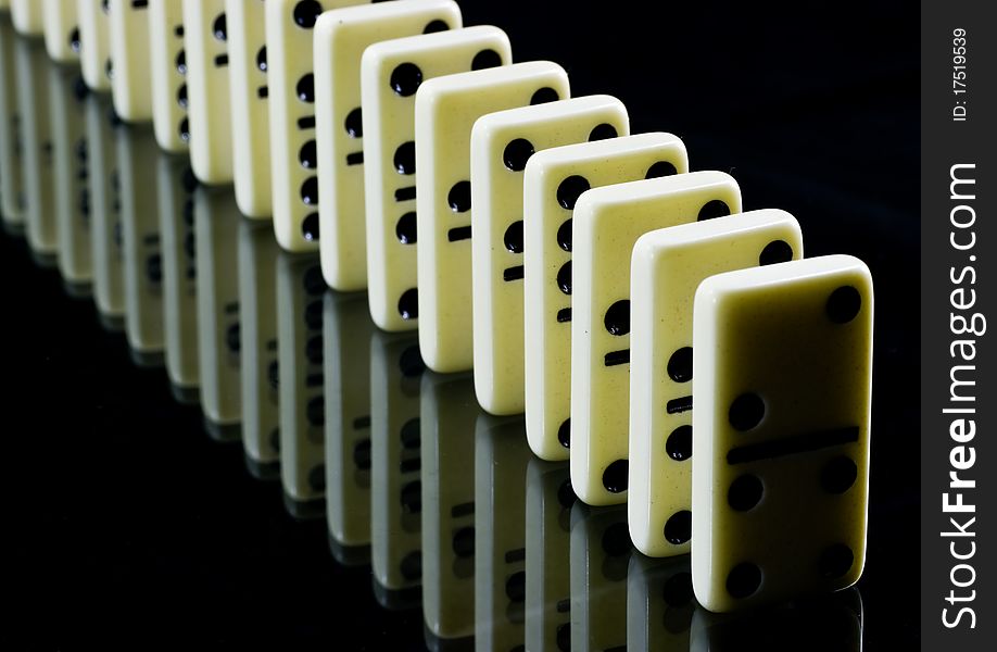 Dominoes waiting to fall, white tiles on black background. Dominoes waiting to fall, white tiles on black background.