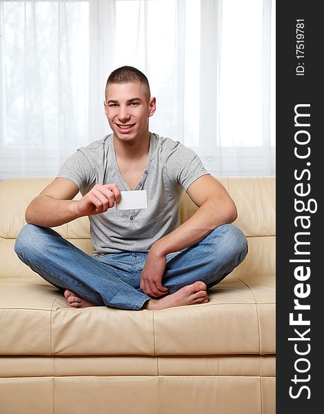 Young man at home with a white businesscard. Young man at home with a white businesscard