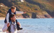 Father Giving Son Ride On Shoulders As They Walk Along Beach By Sea Stock Images
