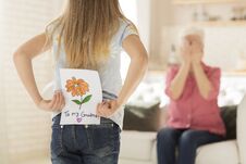 Little Girl With Greeting Card For Granny Behind Her Back, Closeup. Empty Space Royalty Free Stock Images