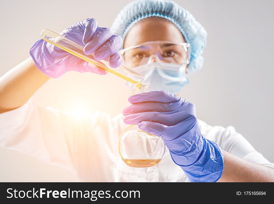 Scientist pouring organic oil. Beauty and cosmetics sciences. Laboratory equipment. White background