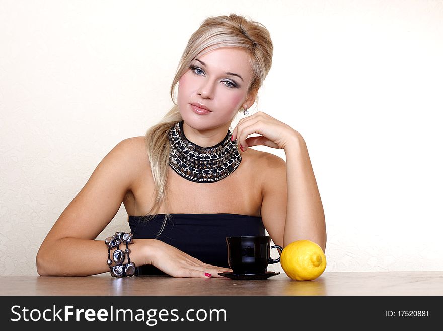 Woman with cup of hot drink with lemon against yellow wall at home