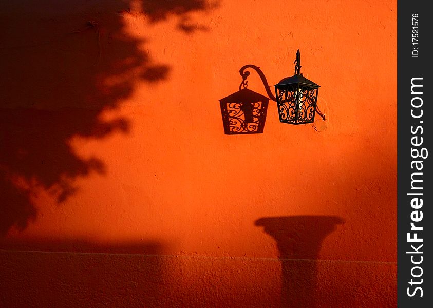 On the bright orange wall hangs a delicate lantern. On the bright orange wall hangs a delicate lantern.