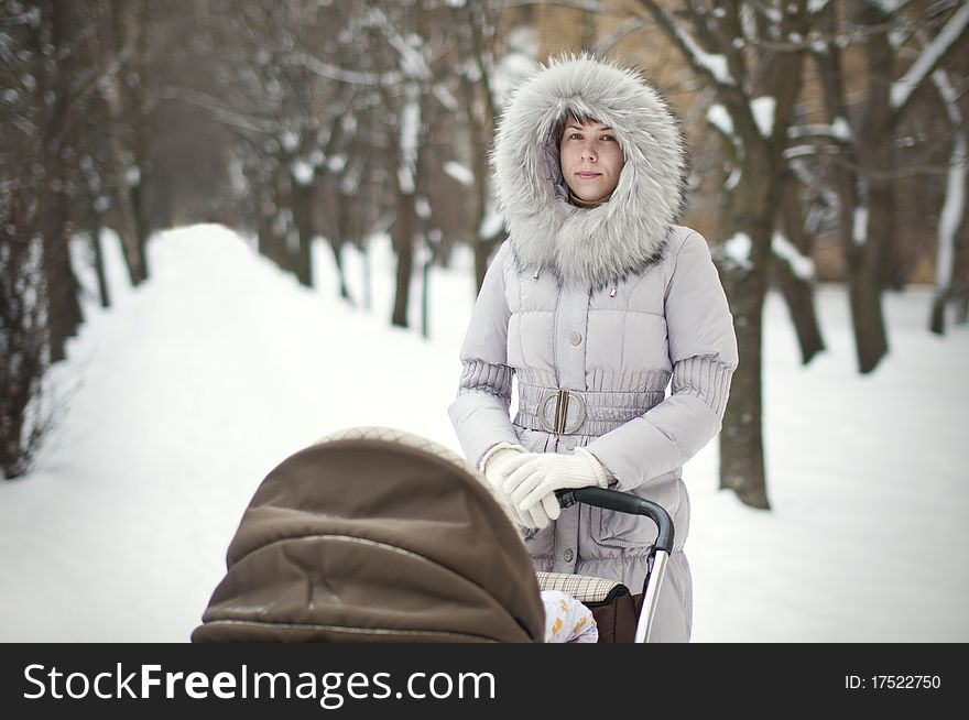 Woman with stroller in a winter park. Woman with stroller in a winter park
