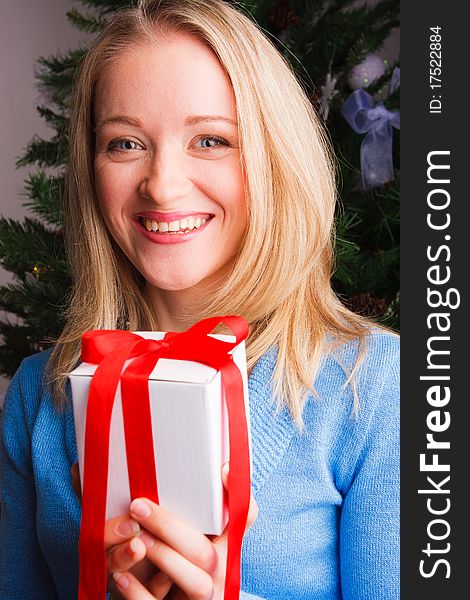 Young woman with a gift near a new-year tree. Young woman with a gift near a new-year tree