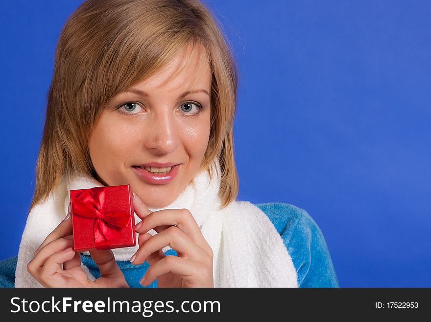 Young merry woman with a gift in hands on a blue background. Young merry woman with a gift in hands on a blue background