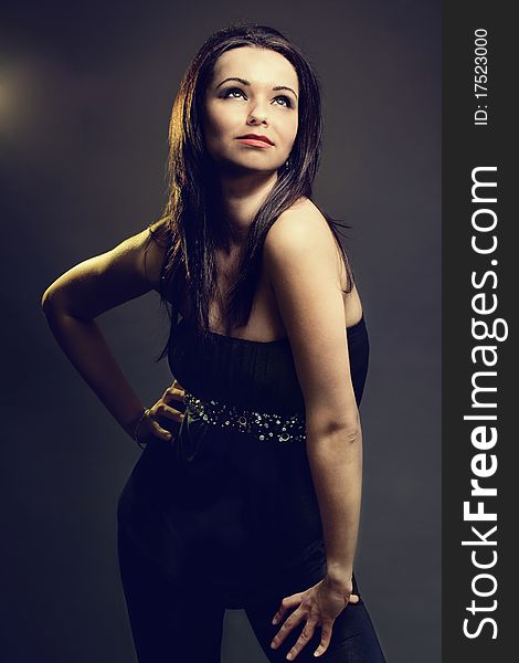 Beautiful brunette woman posing on dark background.