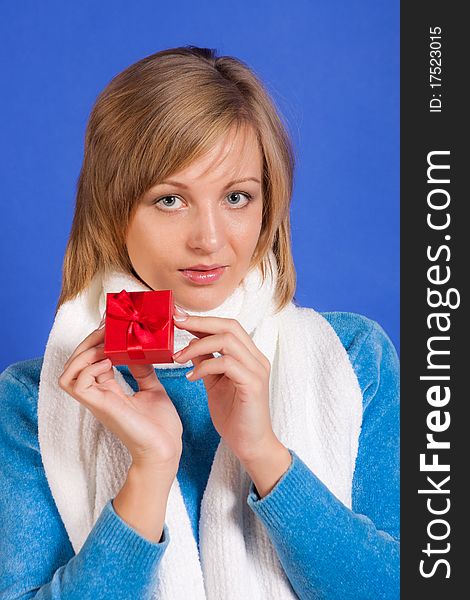 Young merry woman with a gift in hands on a blue background. Young merry woman with a gift in hands on a blue background