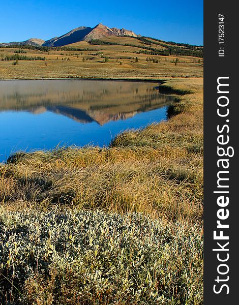 Electric Peak reflects in the blue water of Swan Lake. Yellowstone National Park. Electric Peak reflects in the blue water of Swan Lake. Yellowstone National Park.