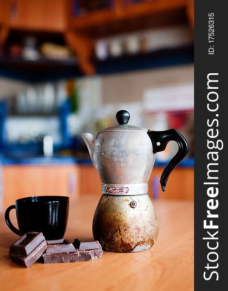 An image of coffee maker with cup and chokolate