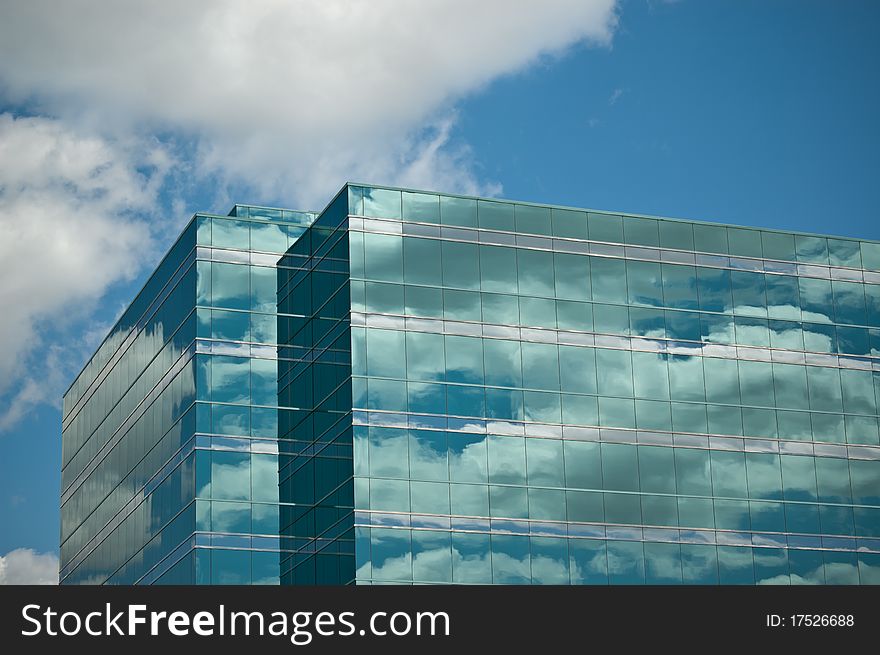 Deep blue sky and clouds are reflected in the shiny windows of this modern office building. Deep blue sky and clouds are reflected in the shiny windows of this modern office building.