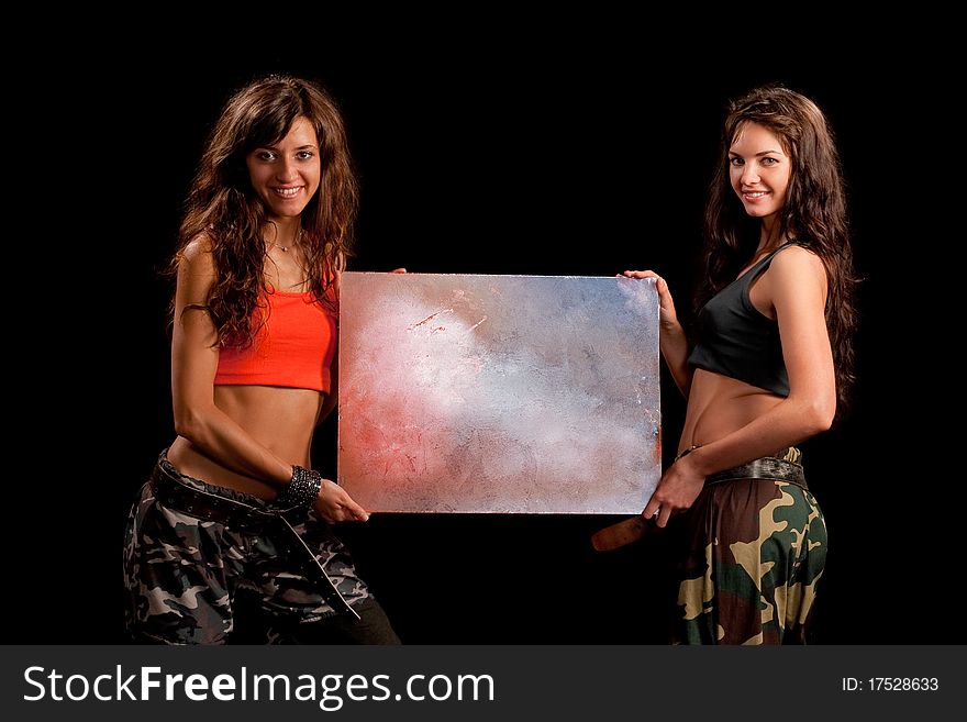 Two girls posing for camera and holds a table like they advertise something. Two girls posing for camera and holds a table like they advertise something