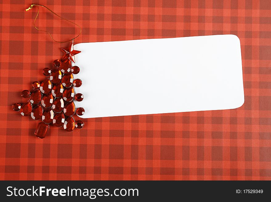 Christmas card with a red decorations in the form of a Christmas tree made of precious stones next to a white sheet of paper