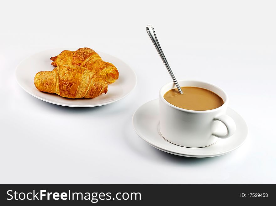 White coffee mug and croissants on plate