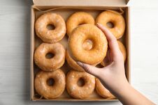 Woman Holding Delicious Donut At White Wooden Table, Top View Royalty Free Stock Photo