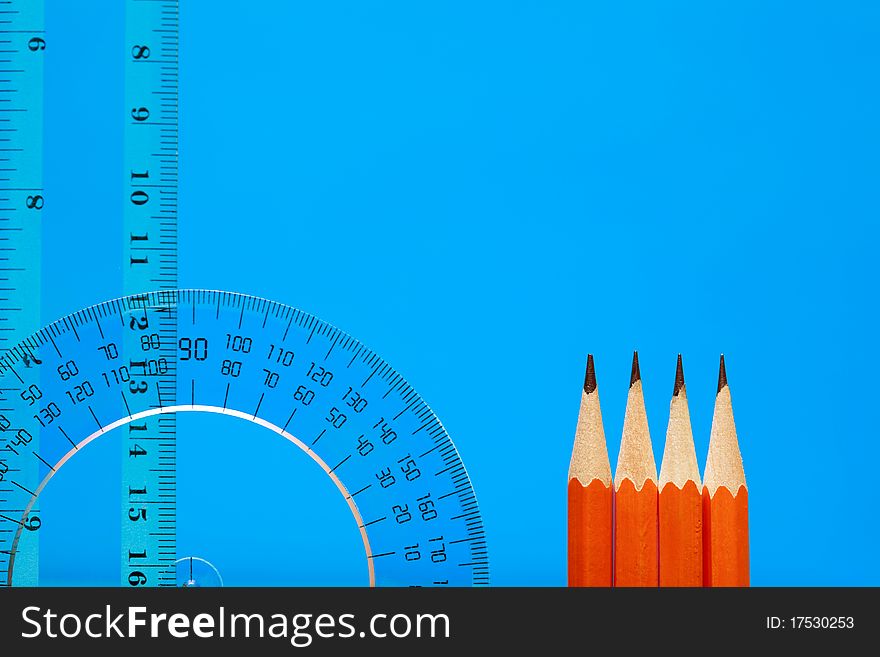 Transparent plastic protractor and ruler near pencils on blue background with copy space. Transparent plastic protractor and ruler near pencils on blue background with copy space