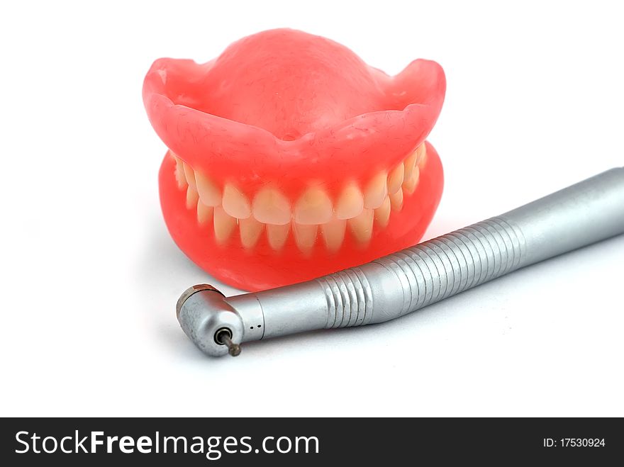 Dentures and handpiece on white background