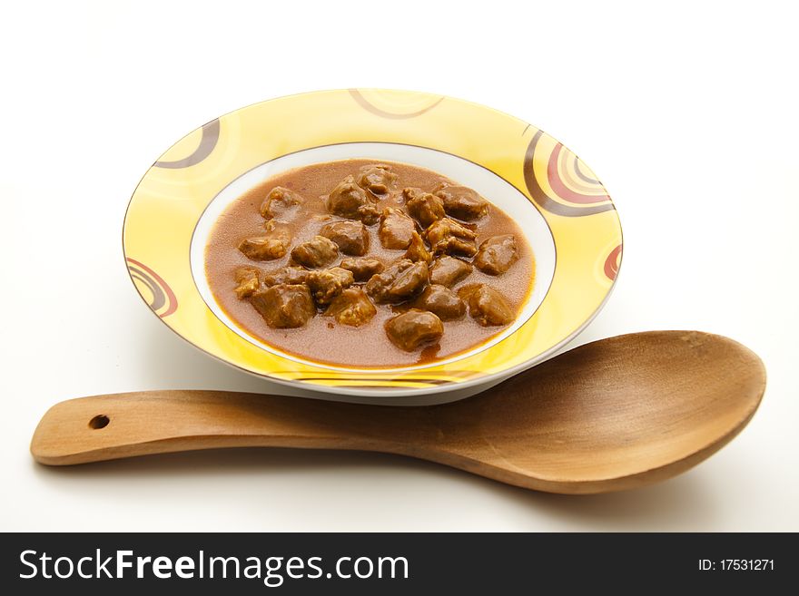 Goulash soup with wooden spoon in the ceramic plate