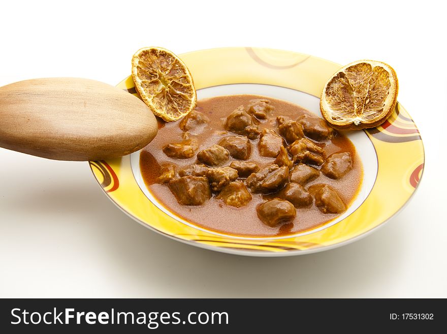 Goulash soup with wooden spoon in the ceramic plate