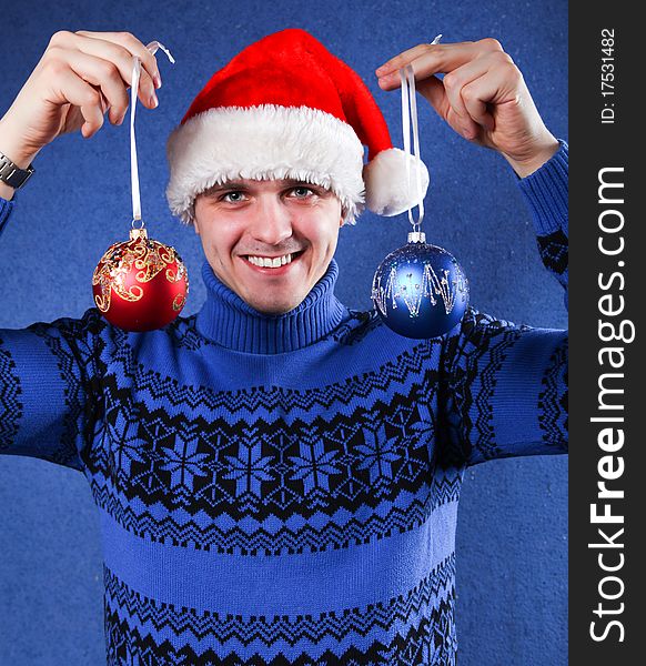 Man in blue sweater and red chrismas hat at blue background. Man in blue sweater and red chrismas hat at blue background