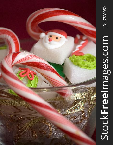 Chirstmas sugar cubes in a glass bowl with candy canes. Chirstmas sugar cubes in a glass bowl with candy canes.