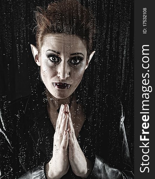 Funny Portrait of a beautiful fashion vampire woman behind rainy window. Funny Portrait of a beautiful fashion vampire woman behind rainy window